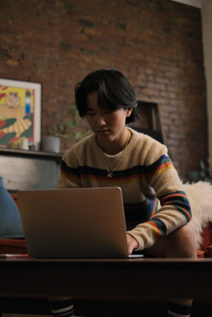 A non-binary person looking at their laptop