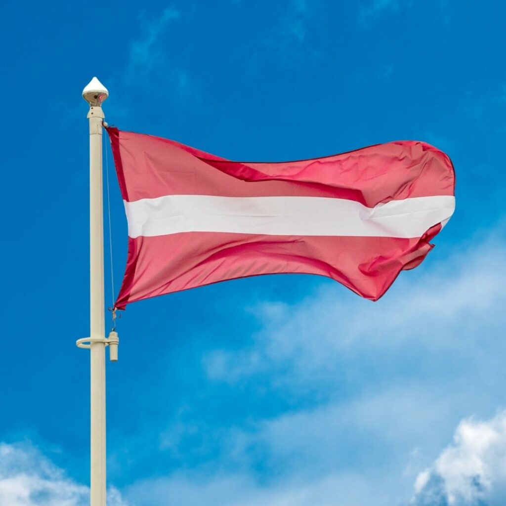 The Latvian flag flies against a blue sky