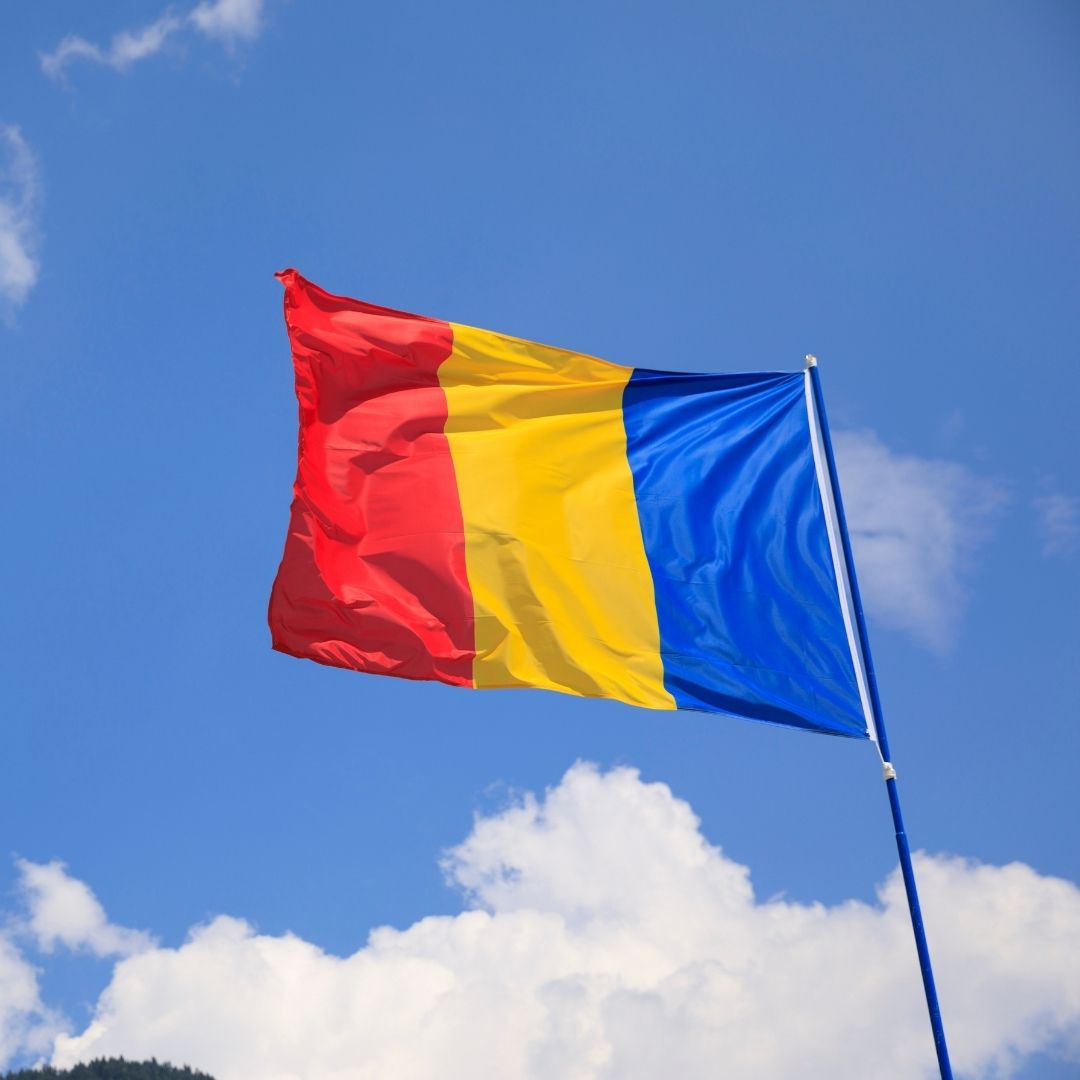 The Romanian flag flies against a blue sky