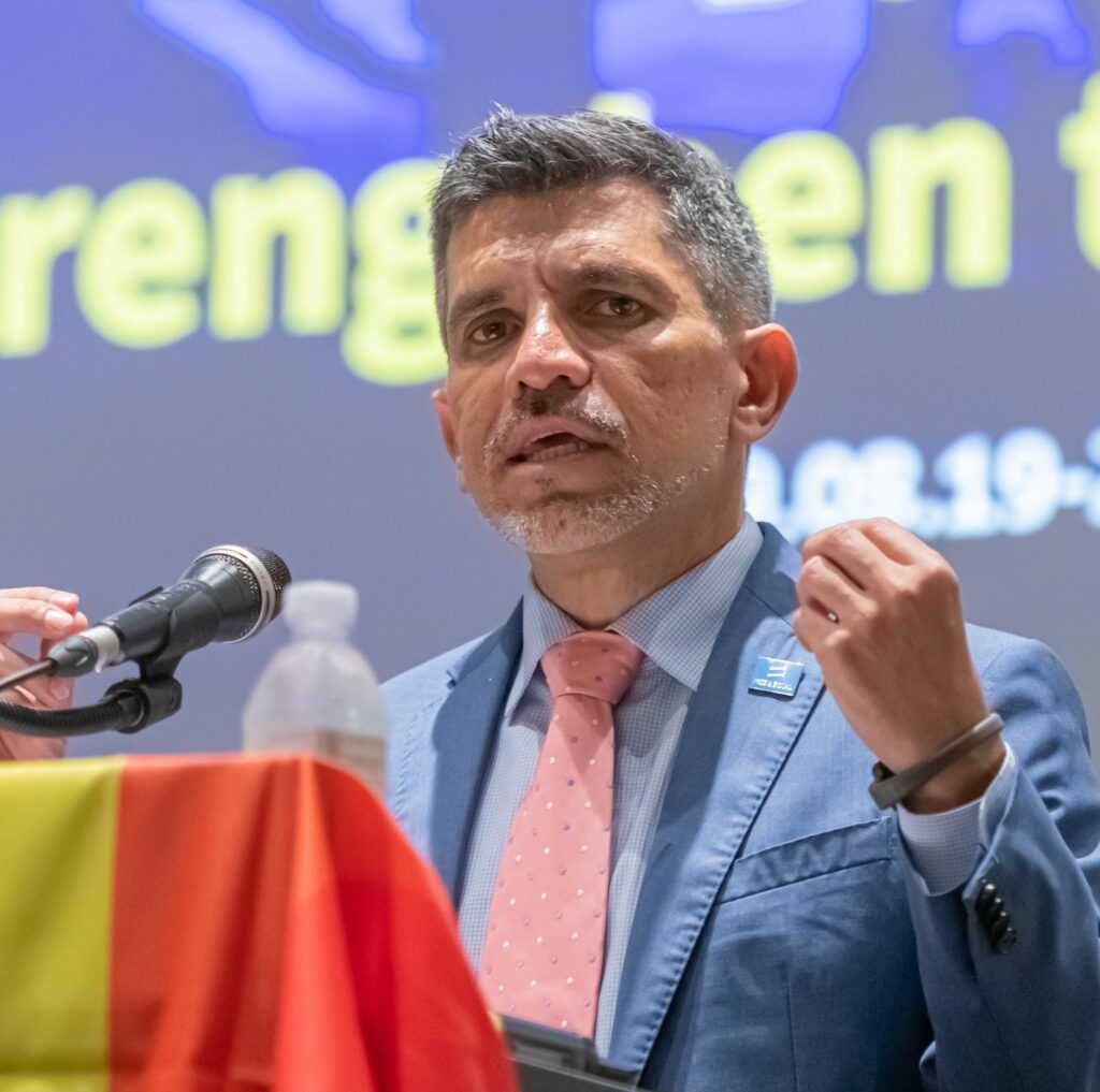 The UN Independent Expert on protection against violence and discrimination based on sexual orientation and gender identity, Victor Madrigal-Borloz gesticulates in at a lectern covered with a rainbow flag