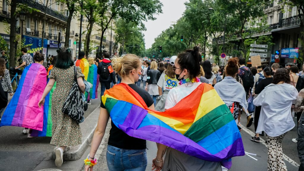 Two people marching with the rainbow flag in Pride March