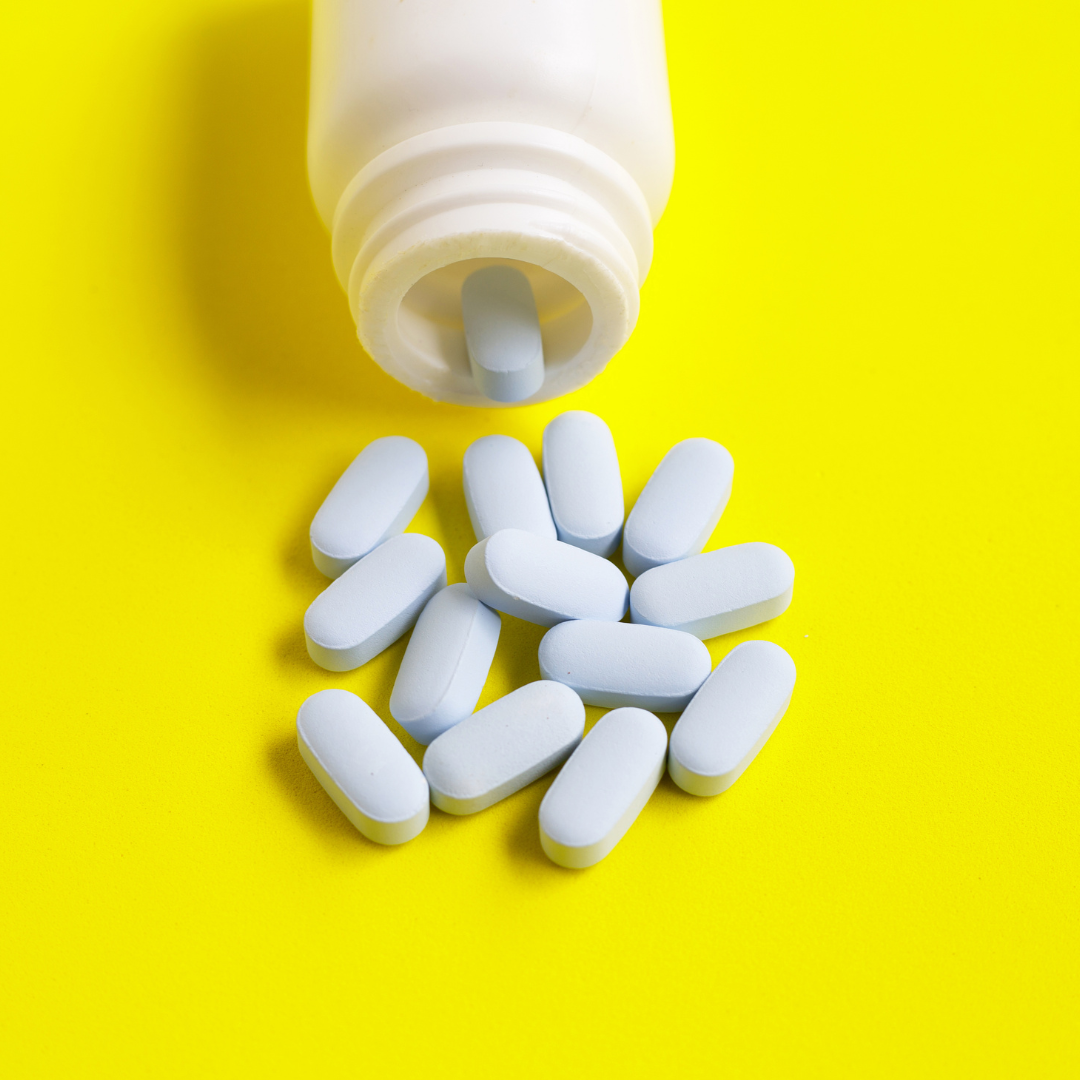 Blue pills, a white pill bottle on a yellow background