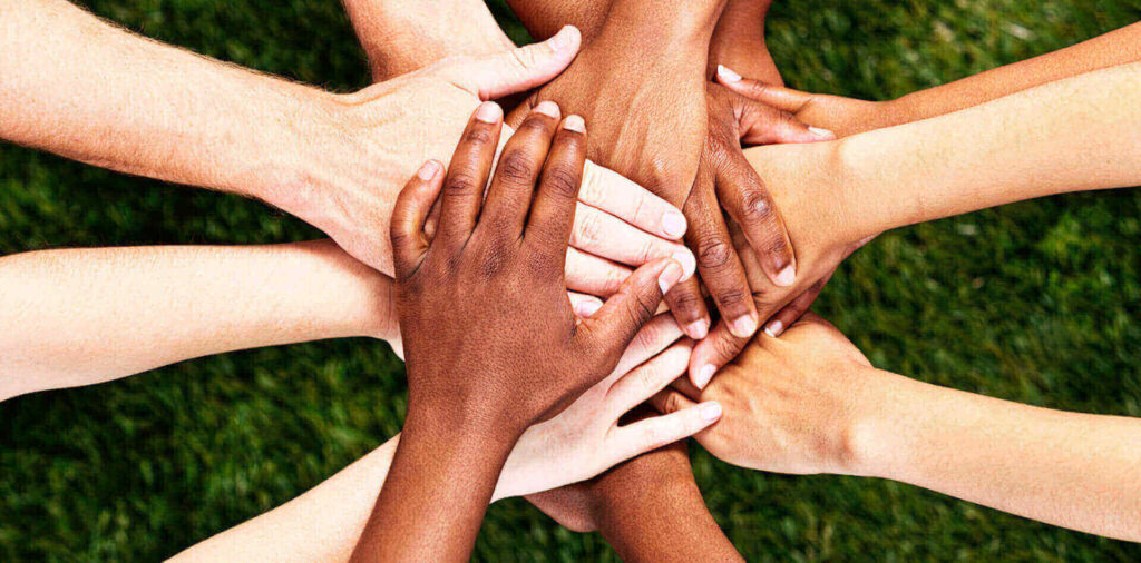 Hands of different skin tones placed together in a circle.