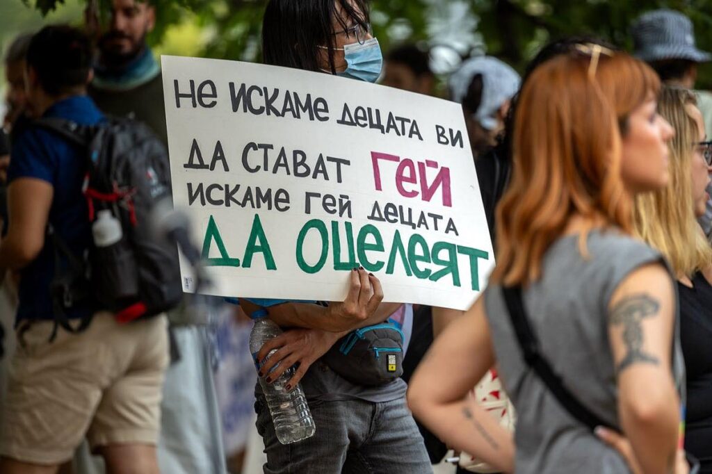 A person holding a sign at a protest with text in Bulgarian that reads: "We don't want your children to become gay. We want gay children to survive."