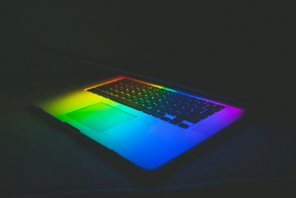 Photo of a laptop keyboard under rainbow lights